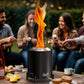 Black 6.5 inch Bali tabletop fire pit with woven flame, friends roasting marshmallows on a patio.